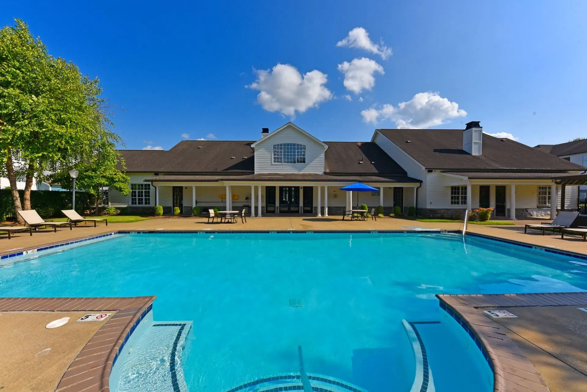 Resort-style swimming pool with lounge chairs and an outdoor seating area.
