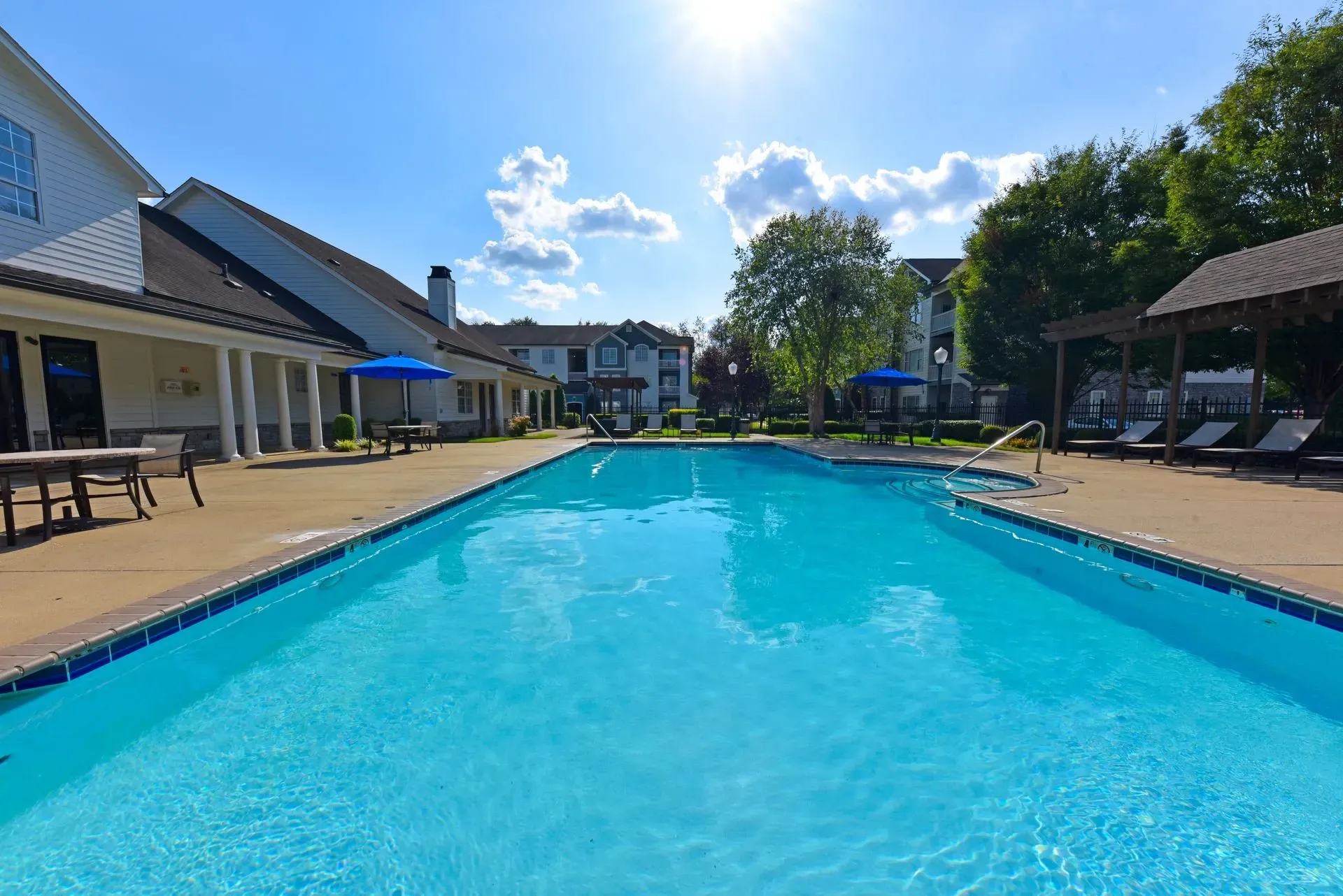 Outdoor swimming pool with lounge chairs and umbrellas.