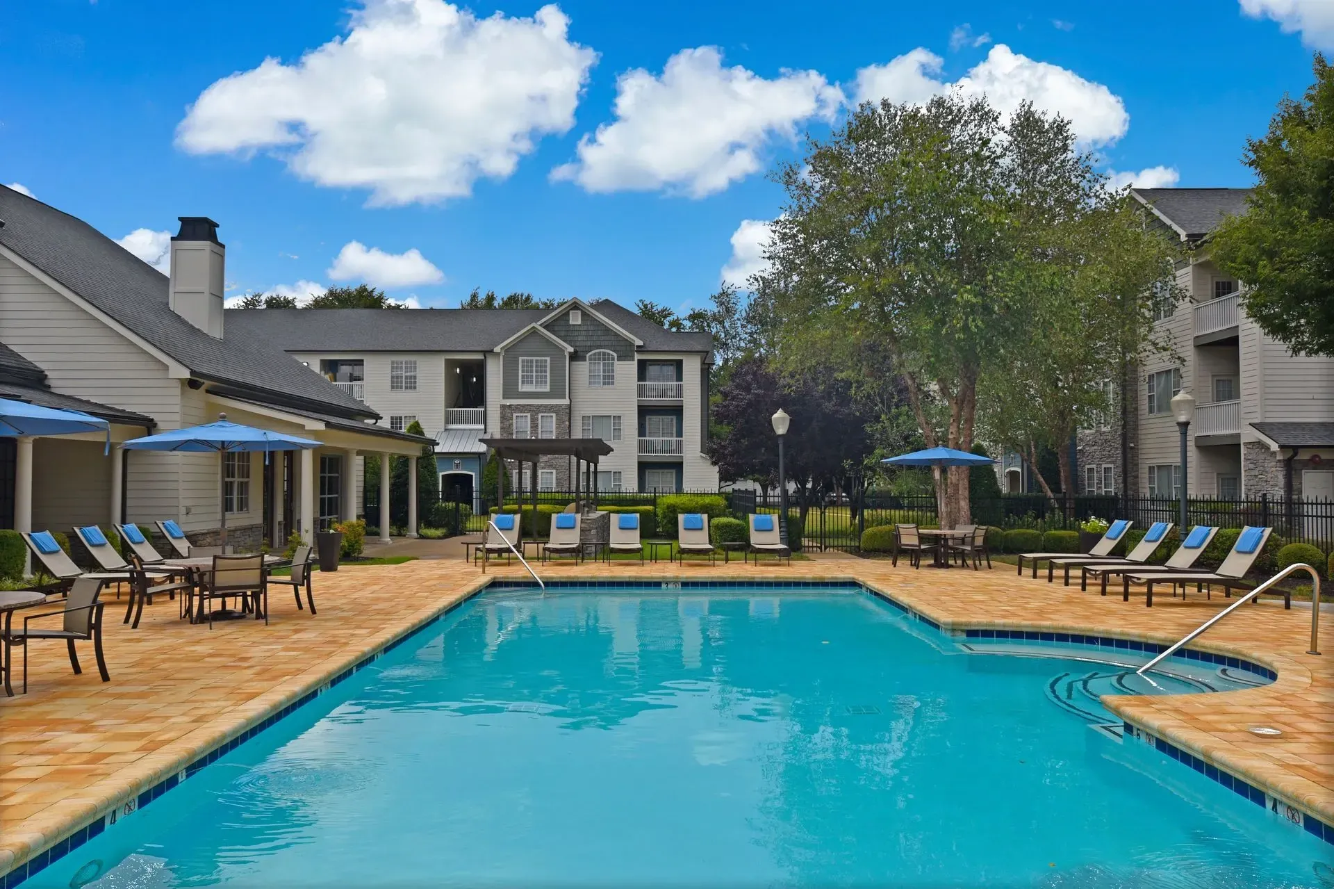 Resort-style outdoor swimming pool with lounge chairs and umbrellas.
