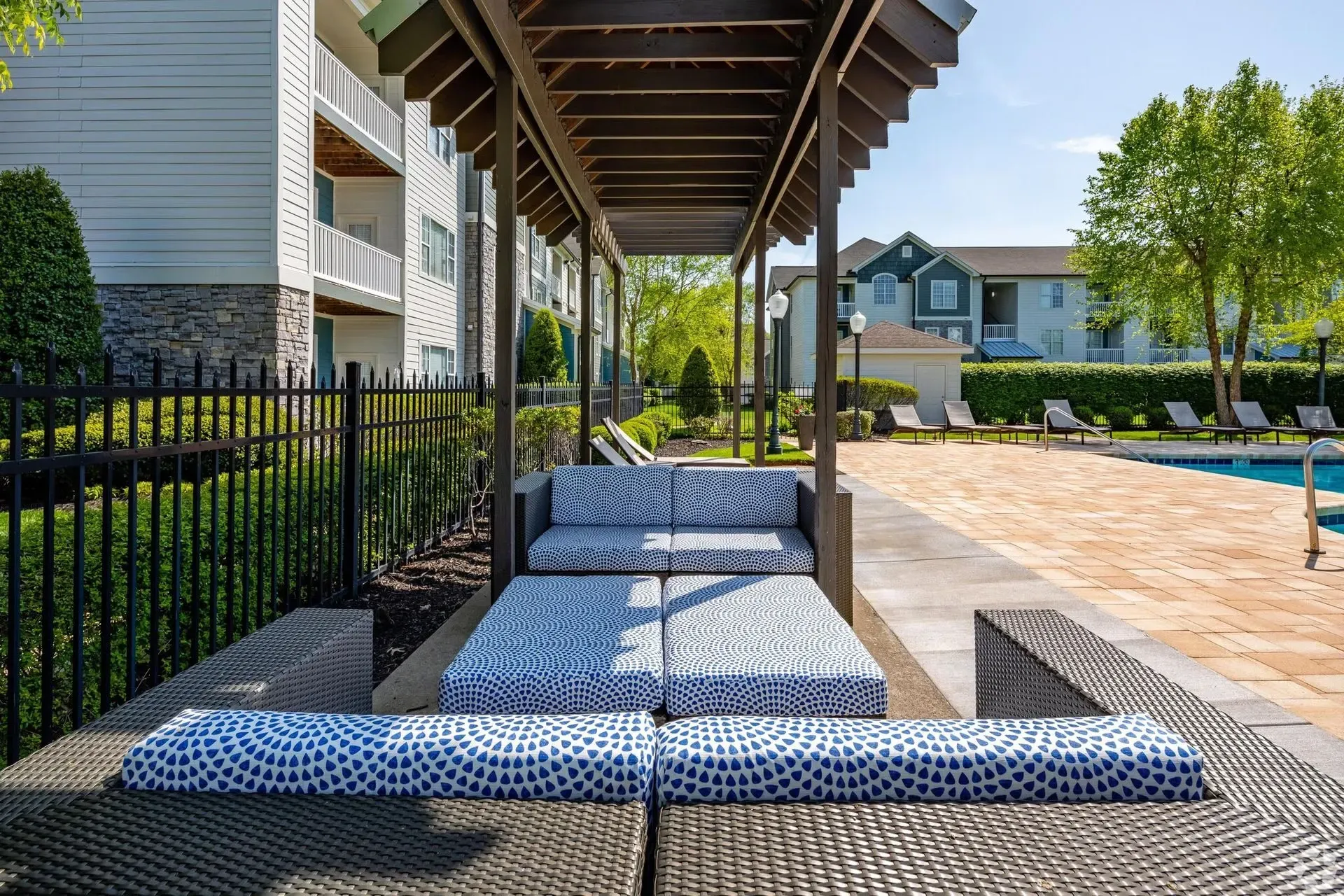 Outdoor pool cabana with lounge seating and swimming pool in the background.