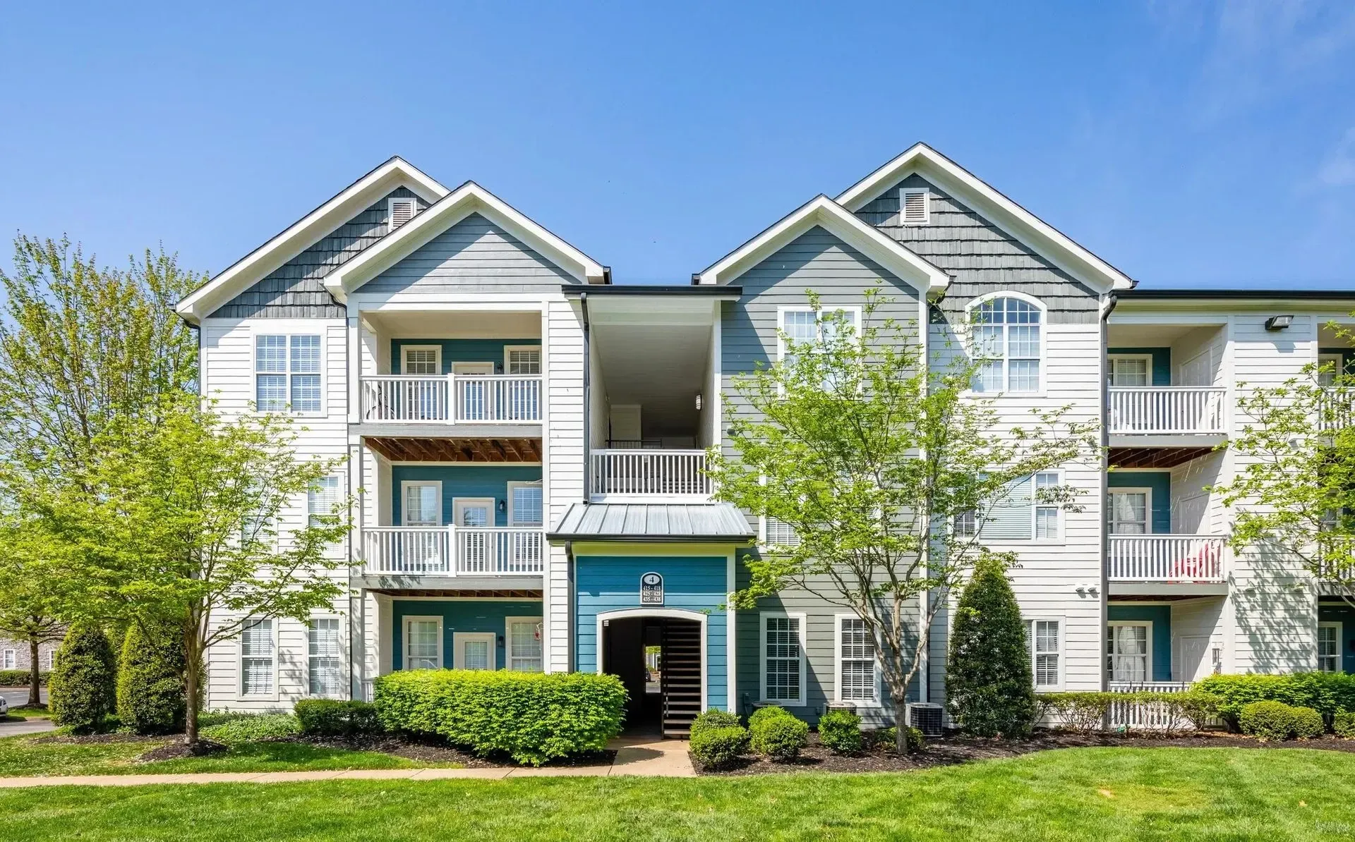 Exterior of an apartment building with balconies and green space.