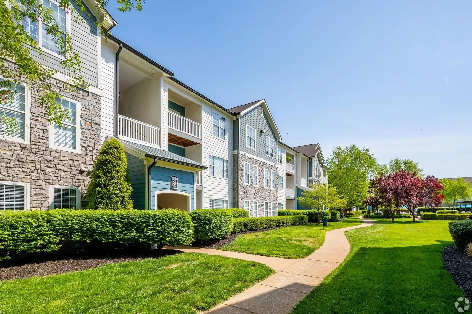 Exterior view of apartment buildings with manicured lawns and pathways.