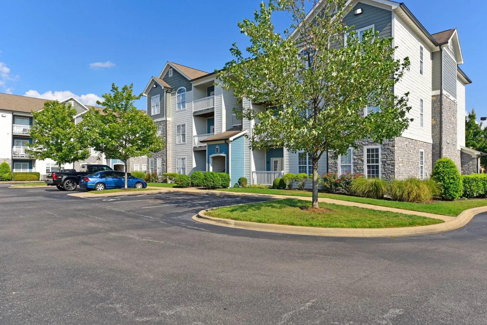 Exterior view of apartment buildings with a parking lot and landscaping.