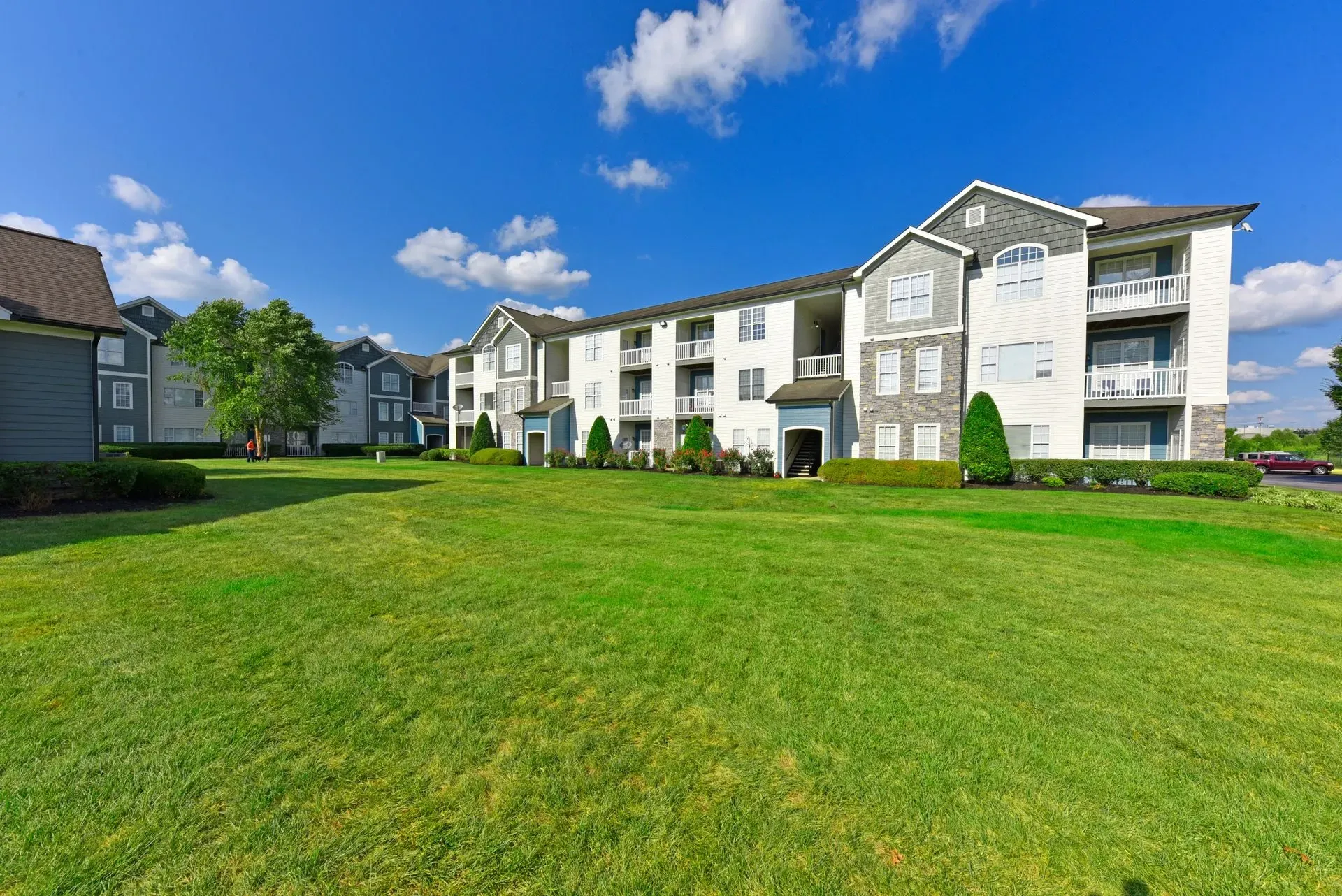 Exterior view of apartment buildings with lush green lawn and blue sky.