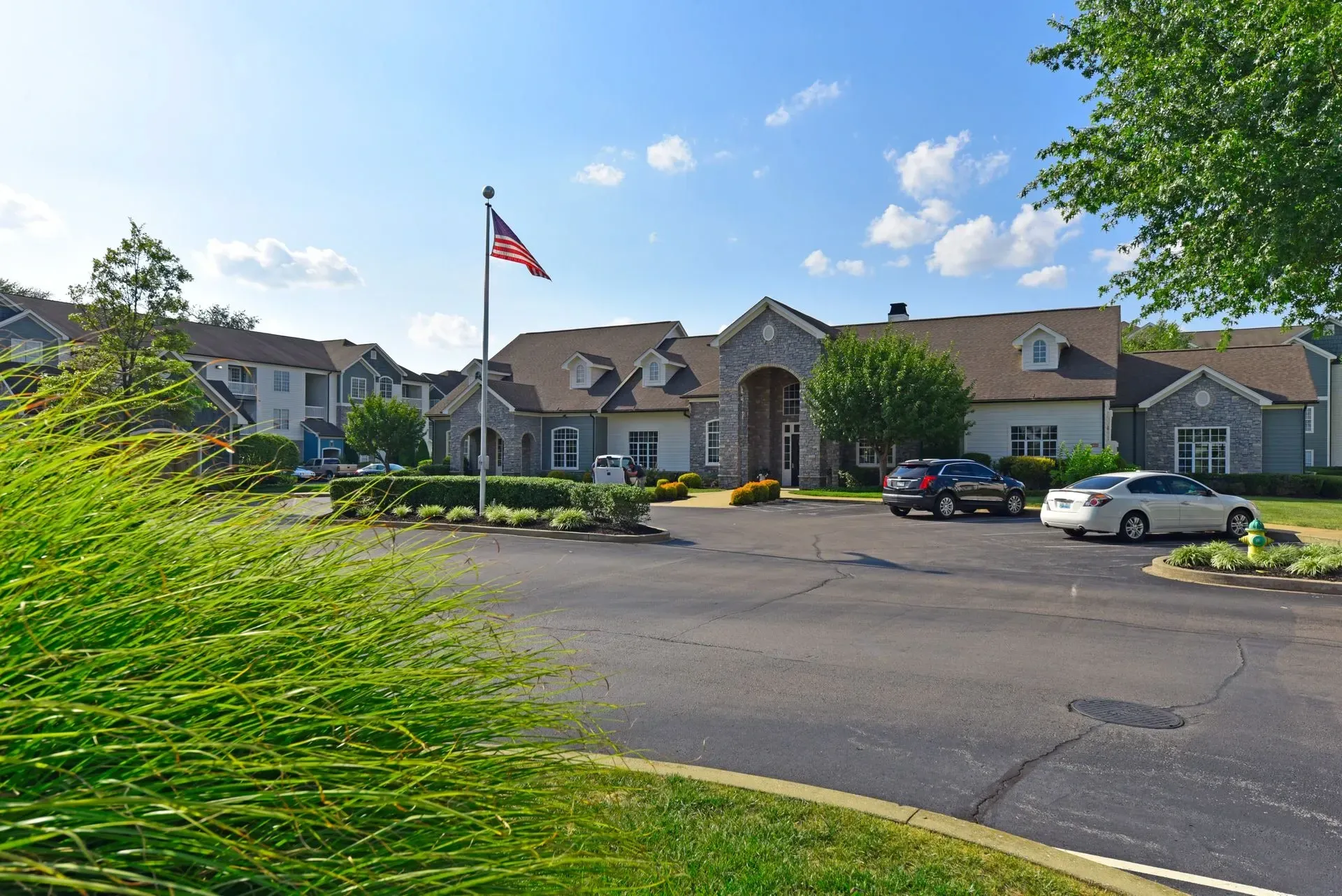 Apartment building exterior with American flag and parking lot.