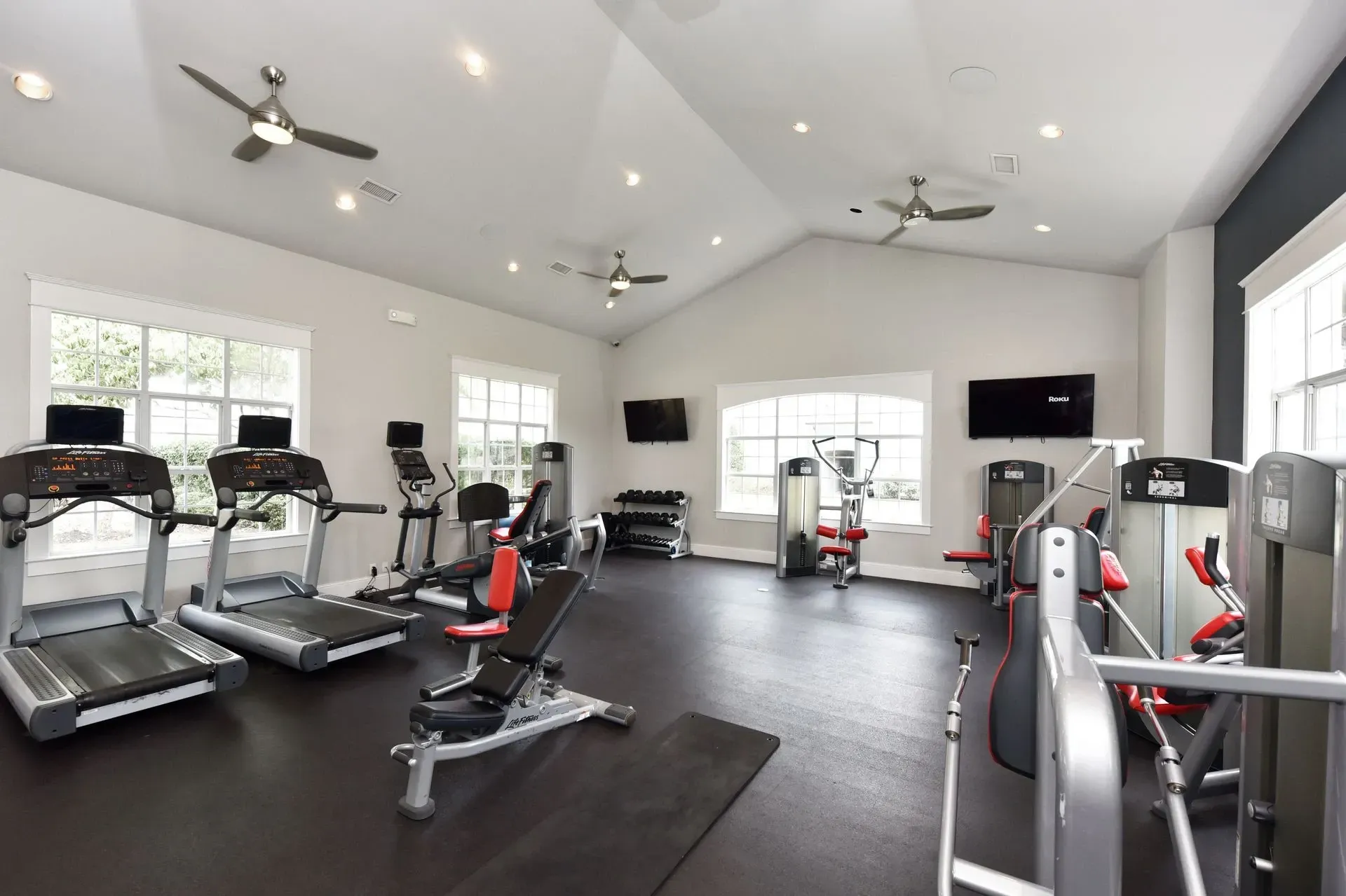 Fitness center with treadmills, elliptical machines, weight machines, and free weights.