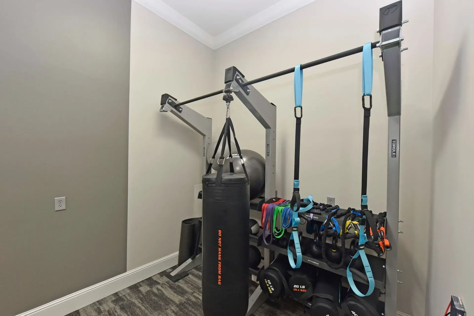 Gym equipment including a punching bag, TRX straps, resistance bands, and weights.