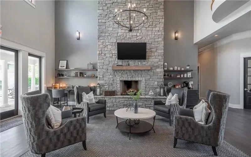 Spacious community lounge area with a stone fireplace, comfortable seating, and modern decor.