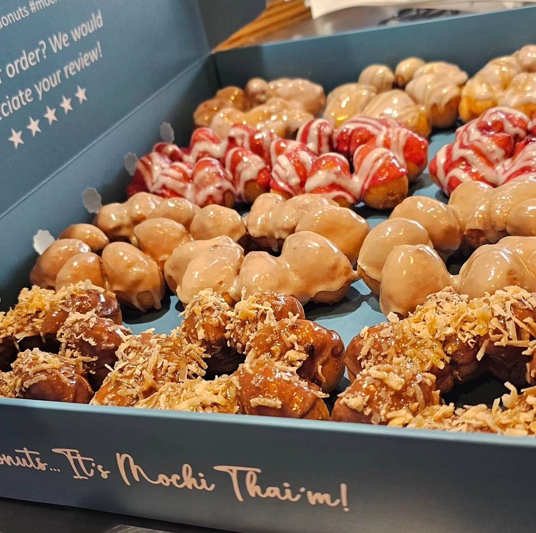 Tray of assorted glazed and chocolate-topped mochi donuts in a bakery box