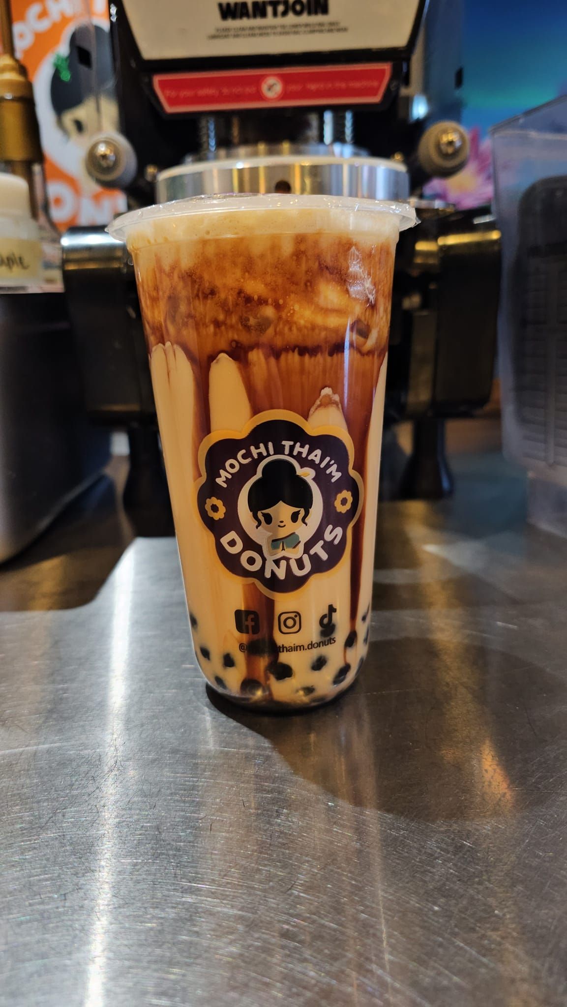 Tall iced bubble tea with caramel swirls and tapioca pearls on a café counter