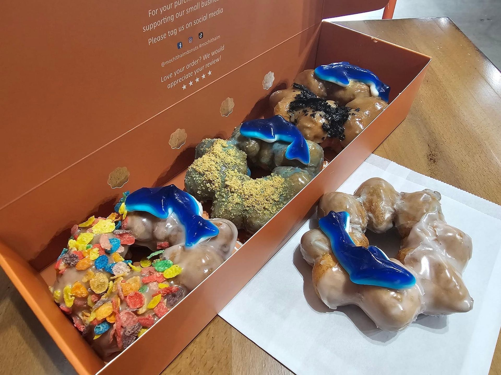 Assorted blue-topped chocolates in a box, with one flower-shaped piece on the table