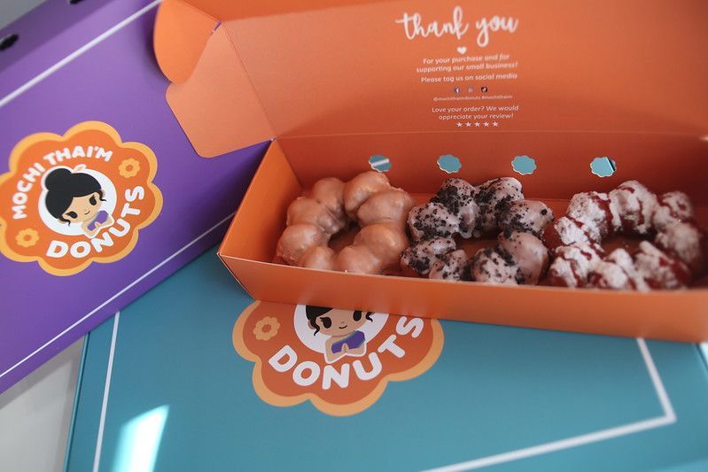 Open orange donut box with assorted donuts on colorful branded packaging