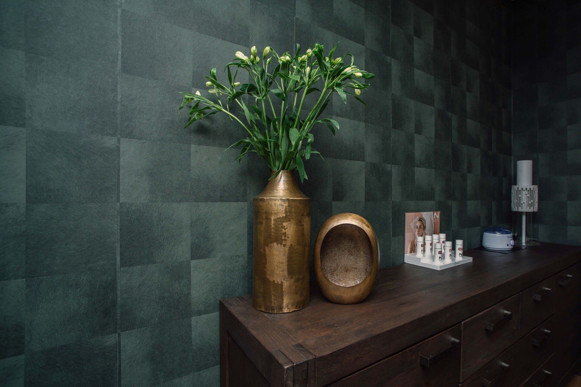 Een vaas met bloemen staat op een houten ladekast in de salon