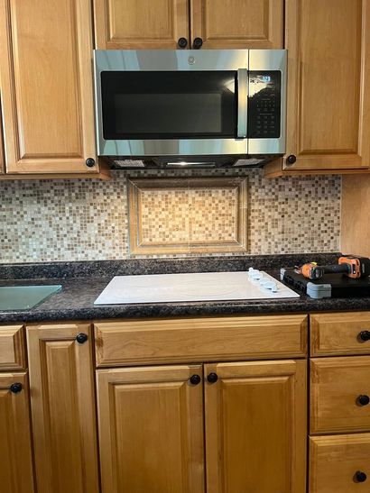 Kitchen with a microwave above a stove, cabinets, and a backsplash.