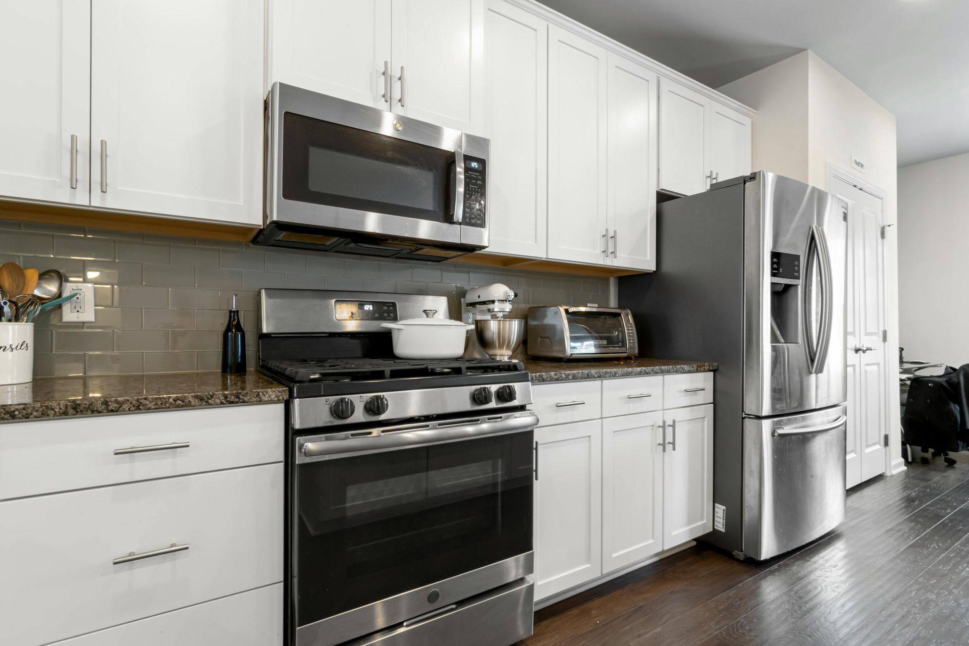 Modern white kitchen with stainless steel appliances and dark wood flooring