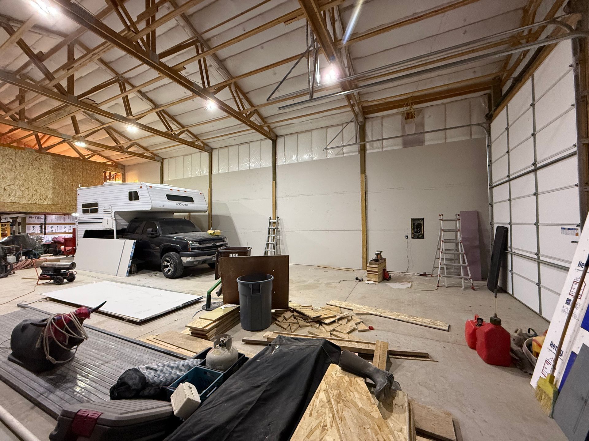 A truck is parked in a garage under concrete construction next to a rv.
