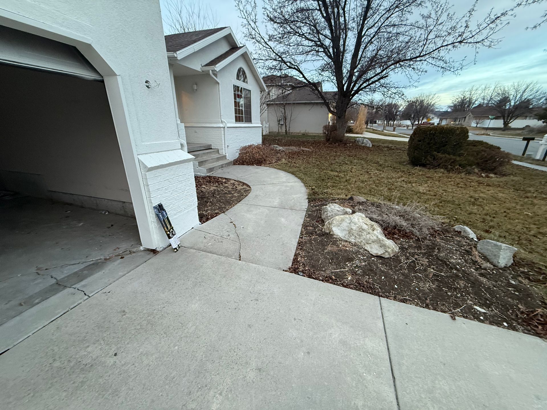 A white house with a newly poured concrete walkway leading to it.