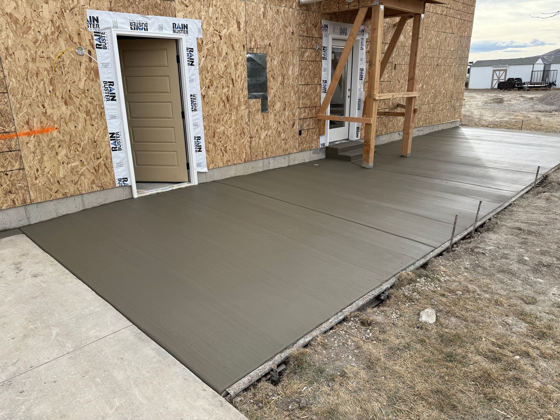 A concrete walkway is being built in front of a house under construction.