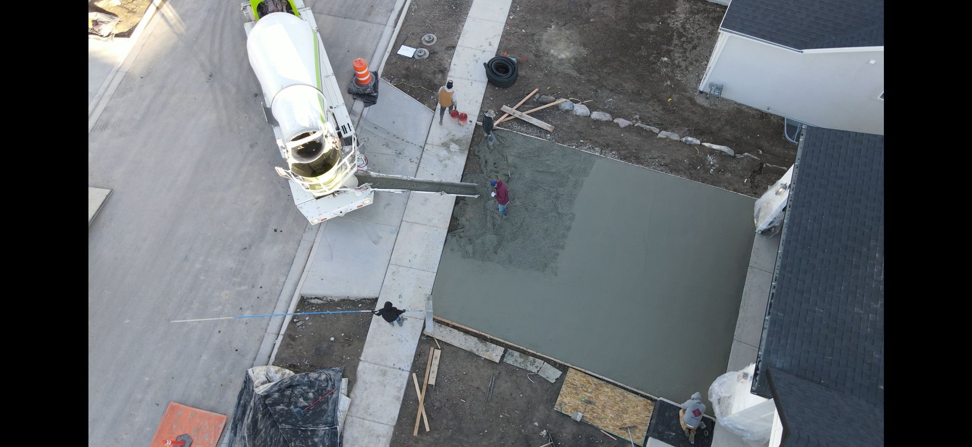 An aerial view of a concrete truck pouring concrete on a sidewalk.