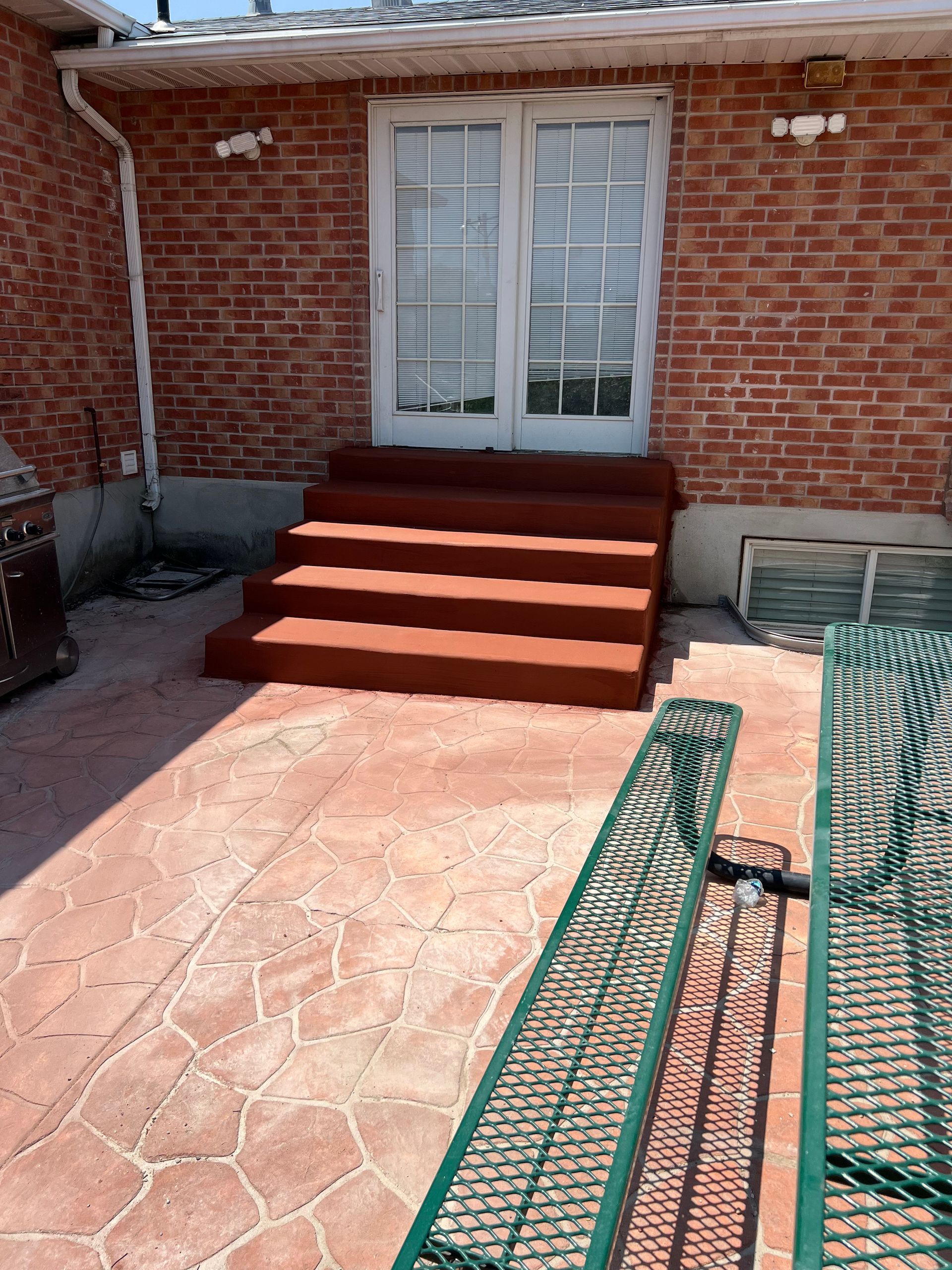 A brick house with a newly built patio and stairs in front of it.