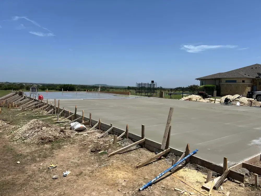 A concrete driveway is being built in front of a house.