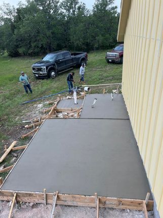 A group of people are working on a concrete walkway in front of a house.