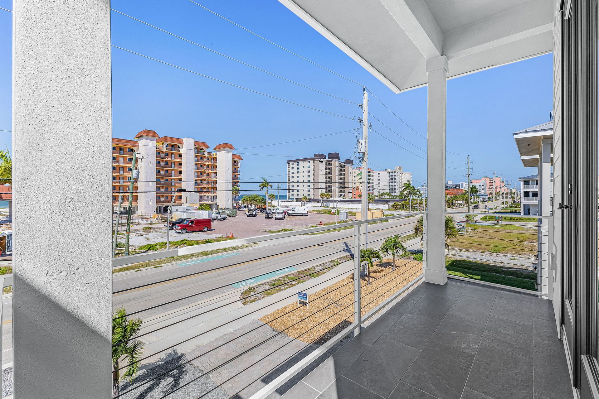 Balcony view of a modern apartment complex and street under a bright blue sky