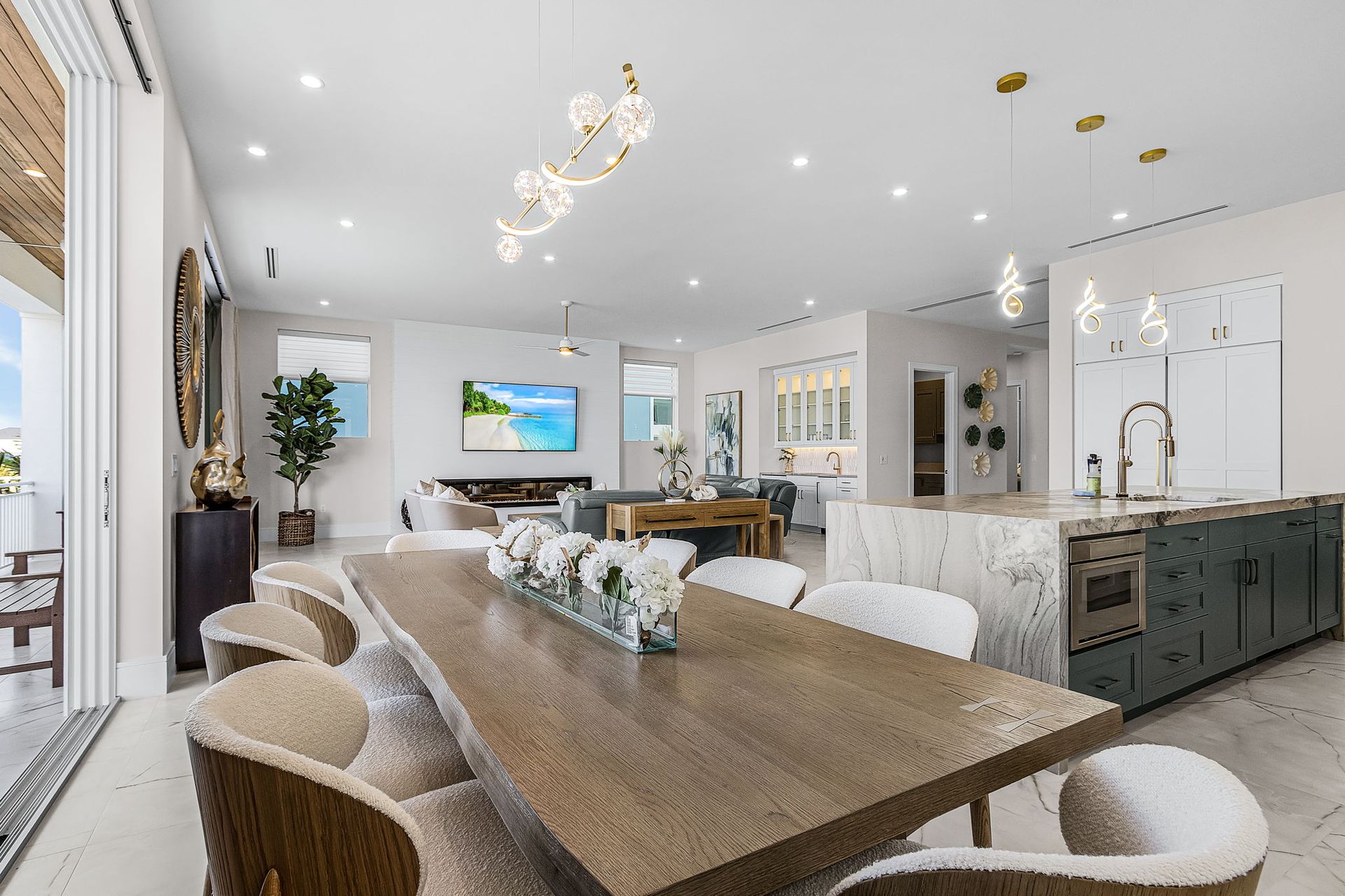 Spacious, modern dining room with long wooden table, plush chairs, and open kitchen.