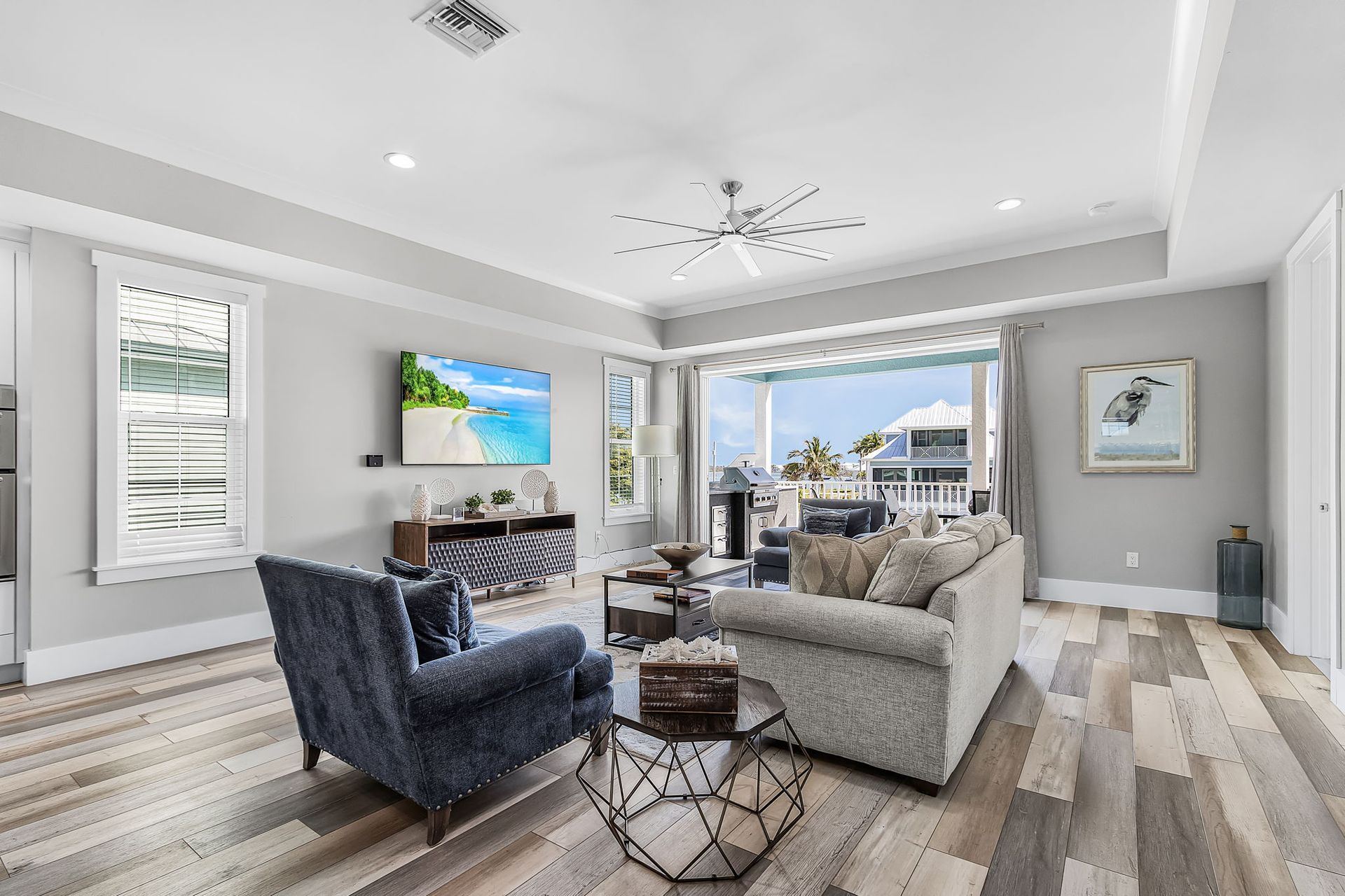 Bright living room with gray sofas, blue chair, fireplace, and ocean-view windows