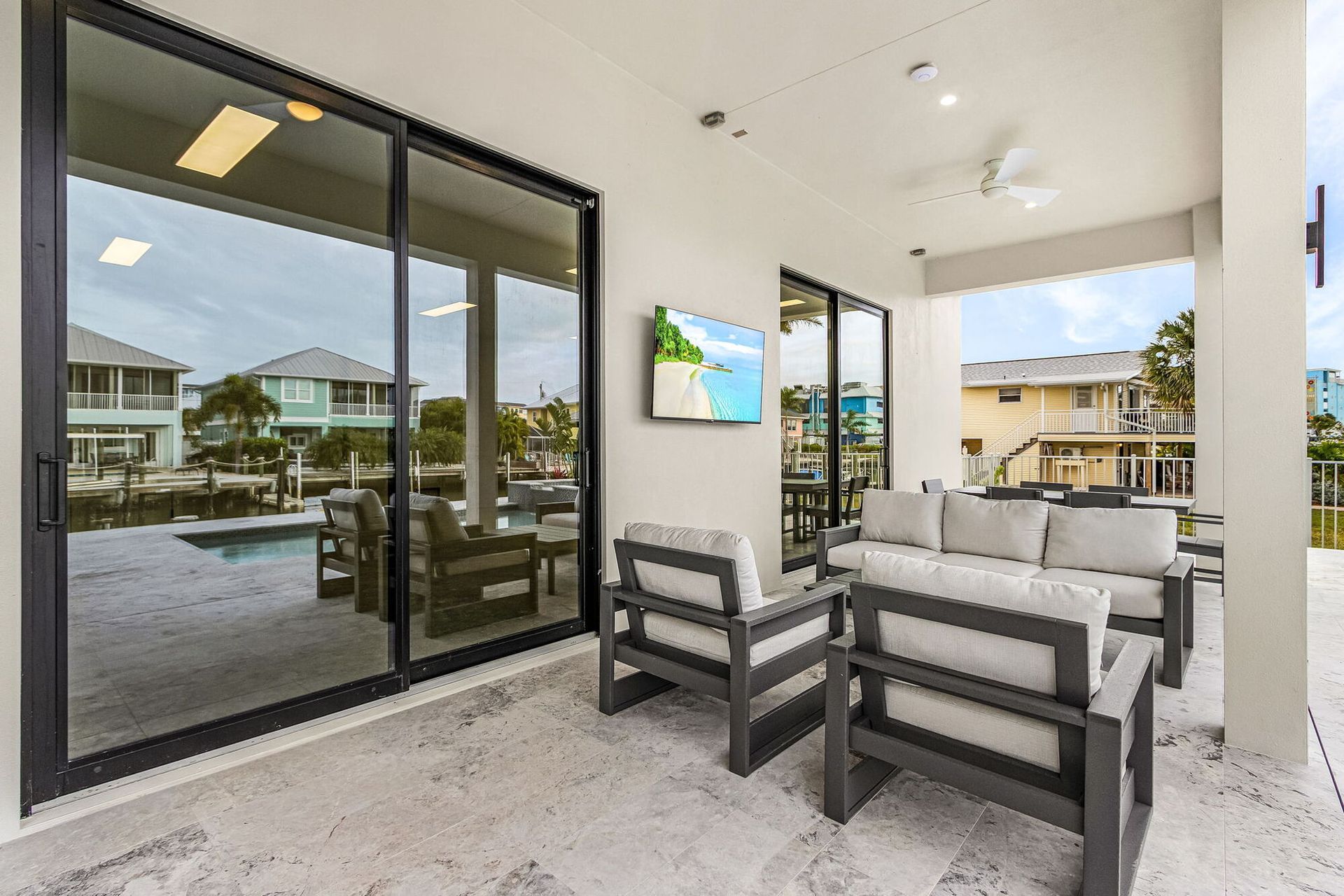 Covered patio with gray outdoor seating and sliding glass doors overlooking a pool area