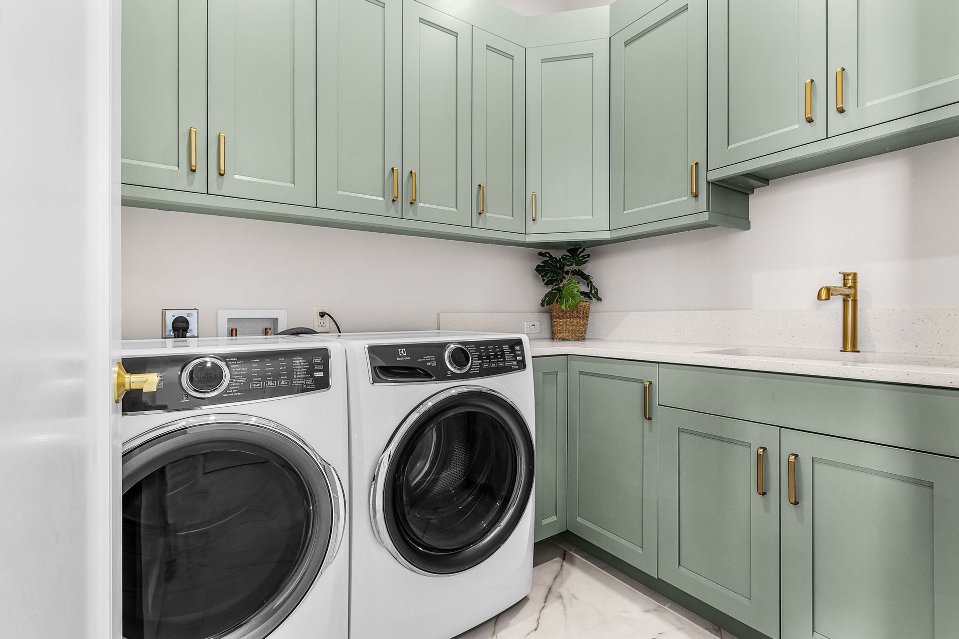 Sage green laundry room with white appliances, cabinets, and countertop.