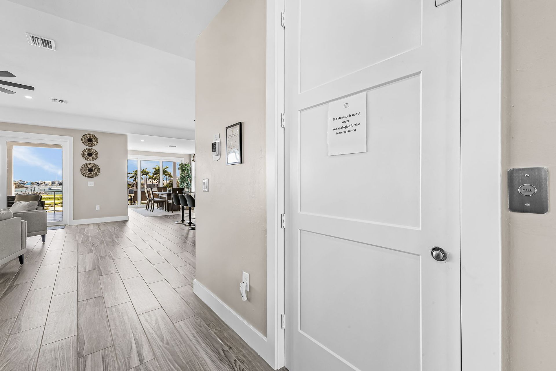 Bright hallway with white doors opening into a sunlit living space with wood floors and seating