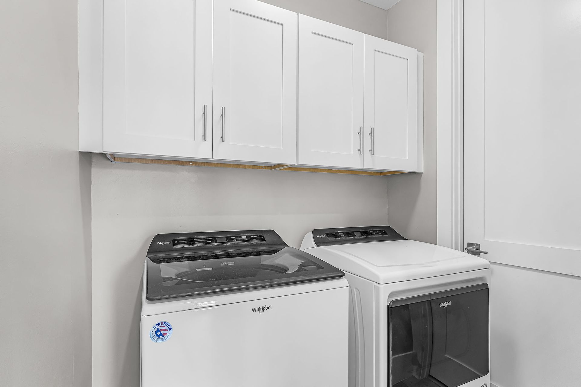 Laundry room with white cabinets and two top-loading washing machines beneath them