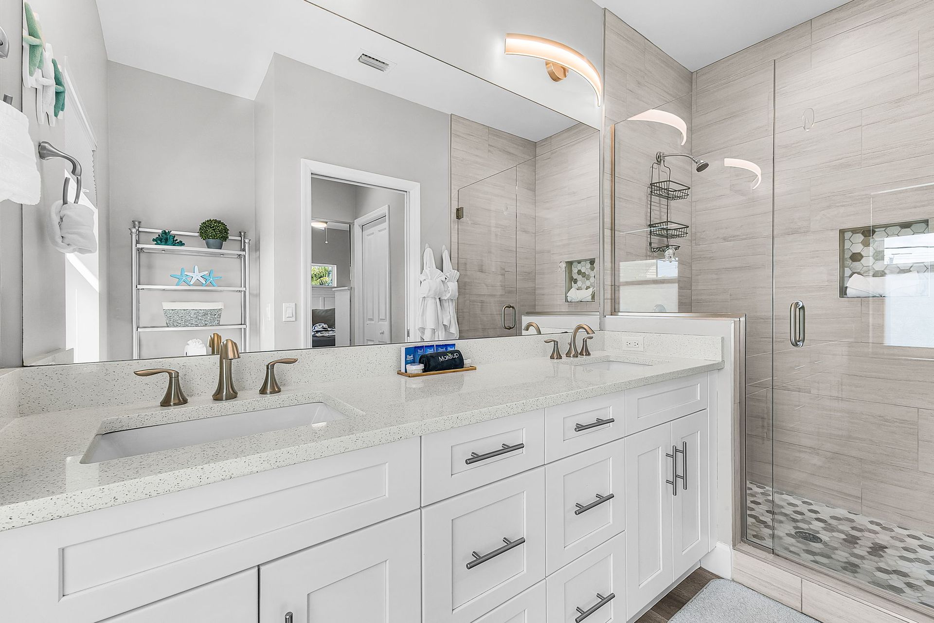 Bright white bathroom with double vanity, large mirror, and glass shower