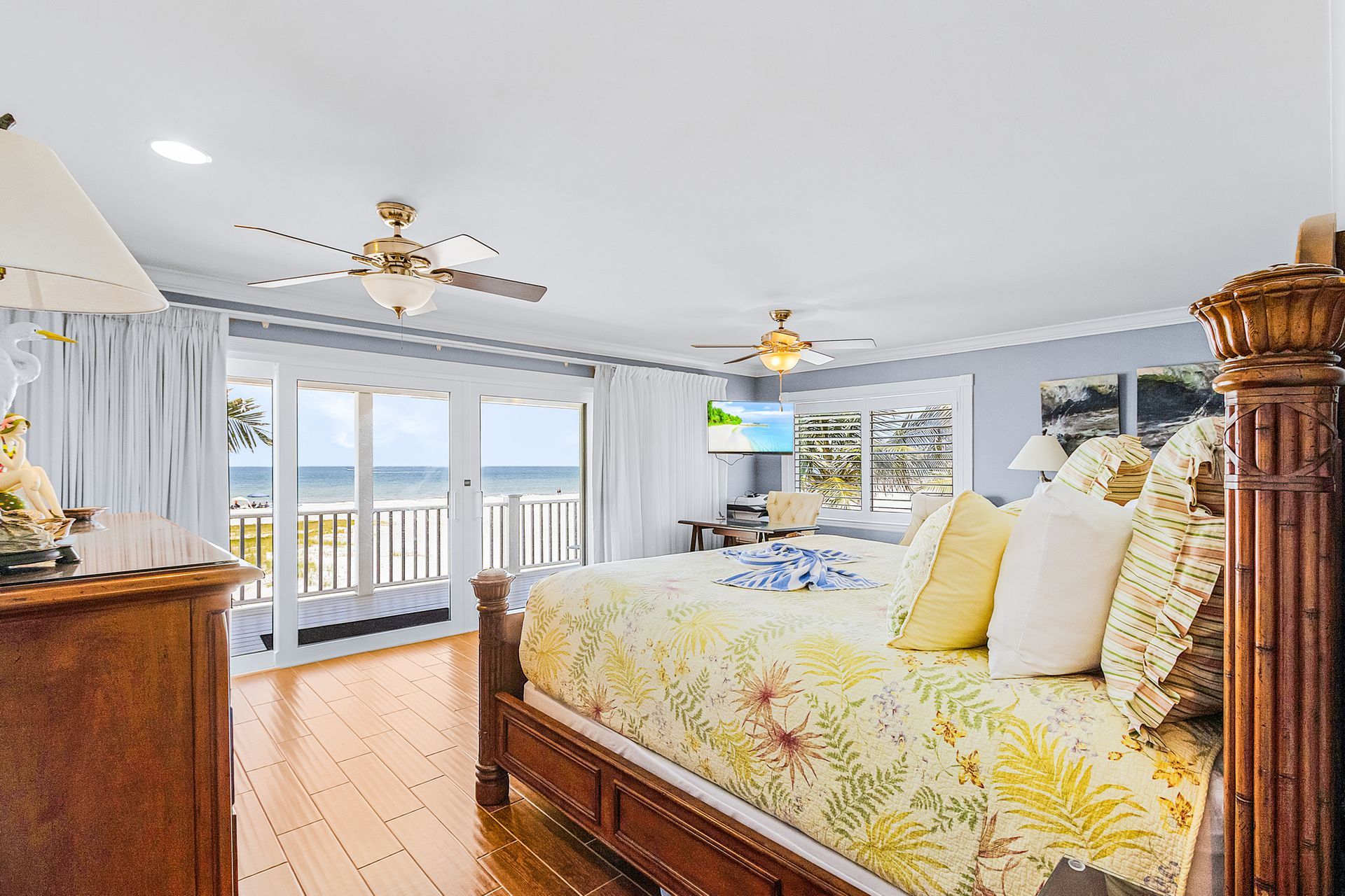 Bright bedroom with floral bedding, wood furniture, and ocean-view sliding doors