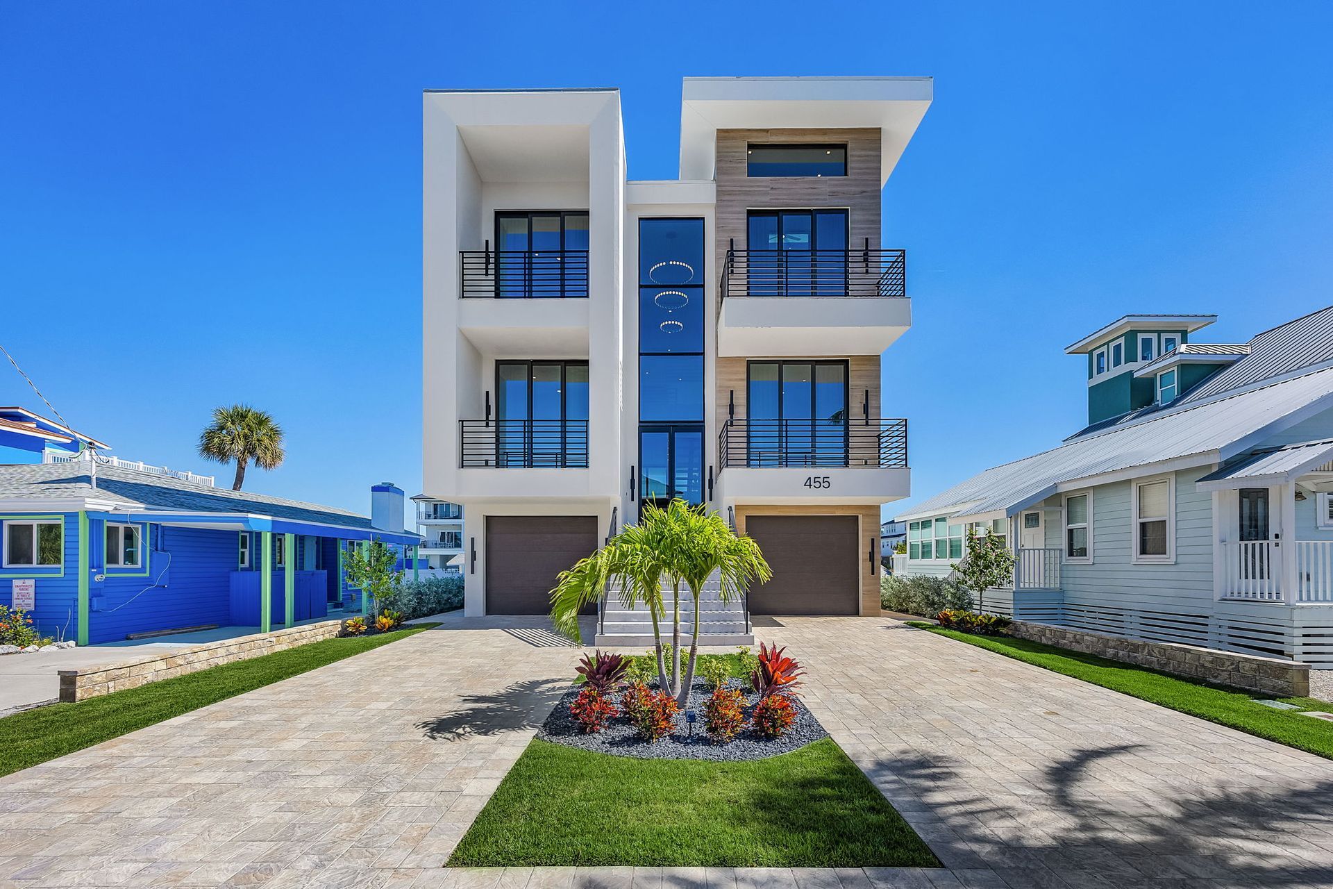 Modern three-story home with balconies, two-car garage, and landscaping.