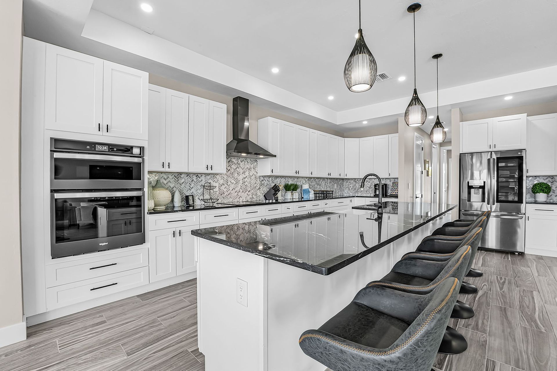 Bright modern kitchen with white cabinets, black island, and pendant lights