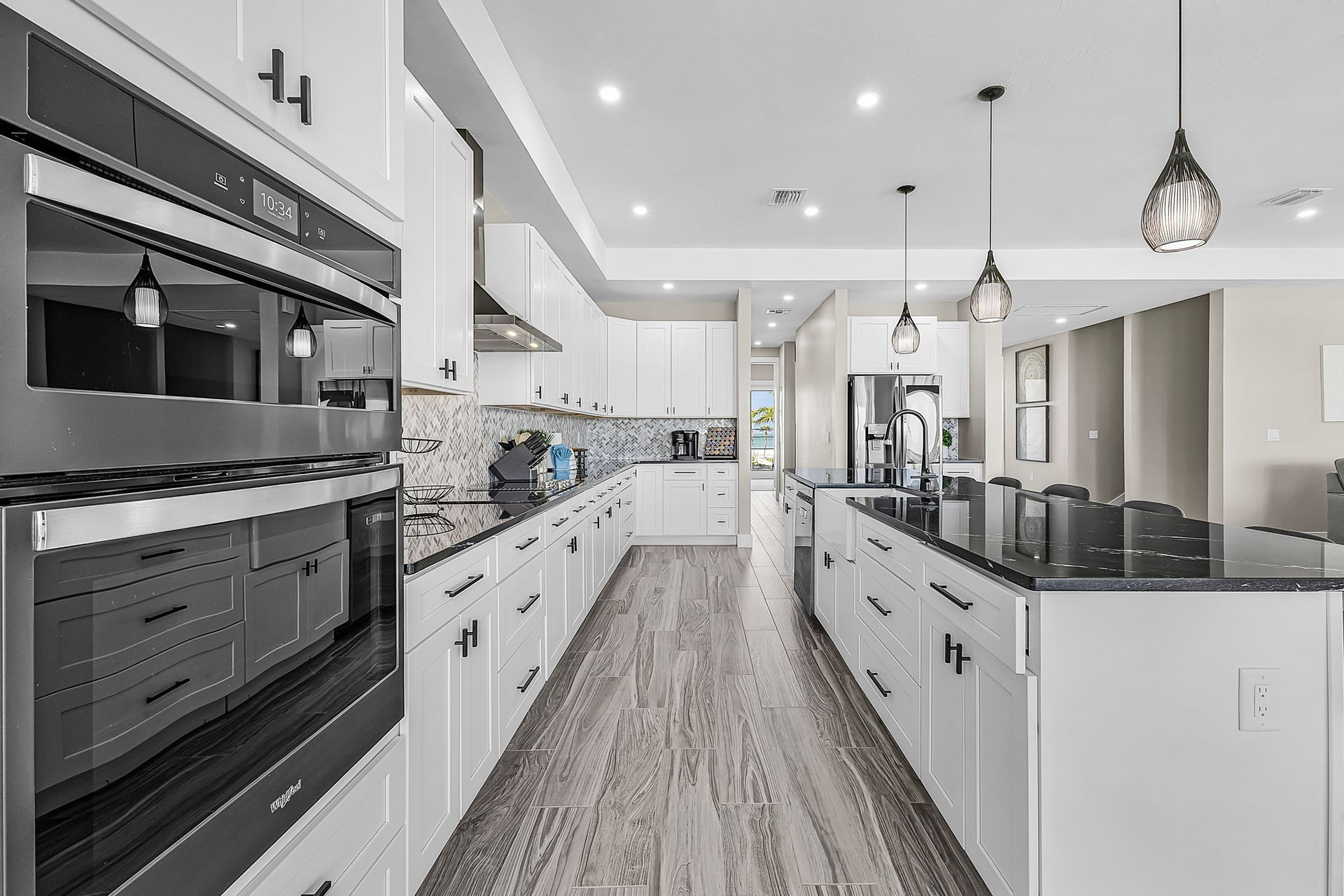 Bright modern white kitchen with island, built-in ovens, and pendant lights