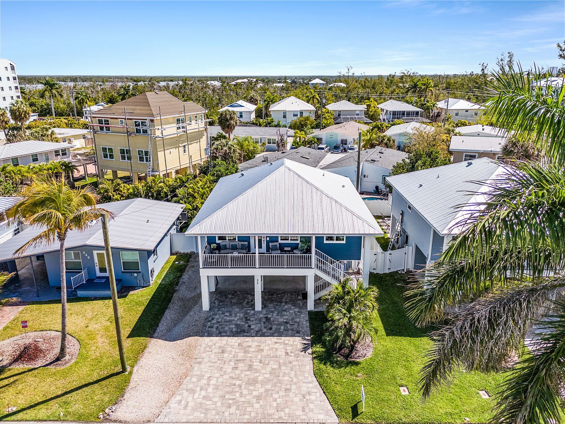 Coastal neighborhood with white houses, palm trees, and a bright blue ocean in the distance