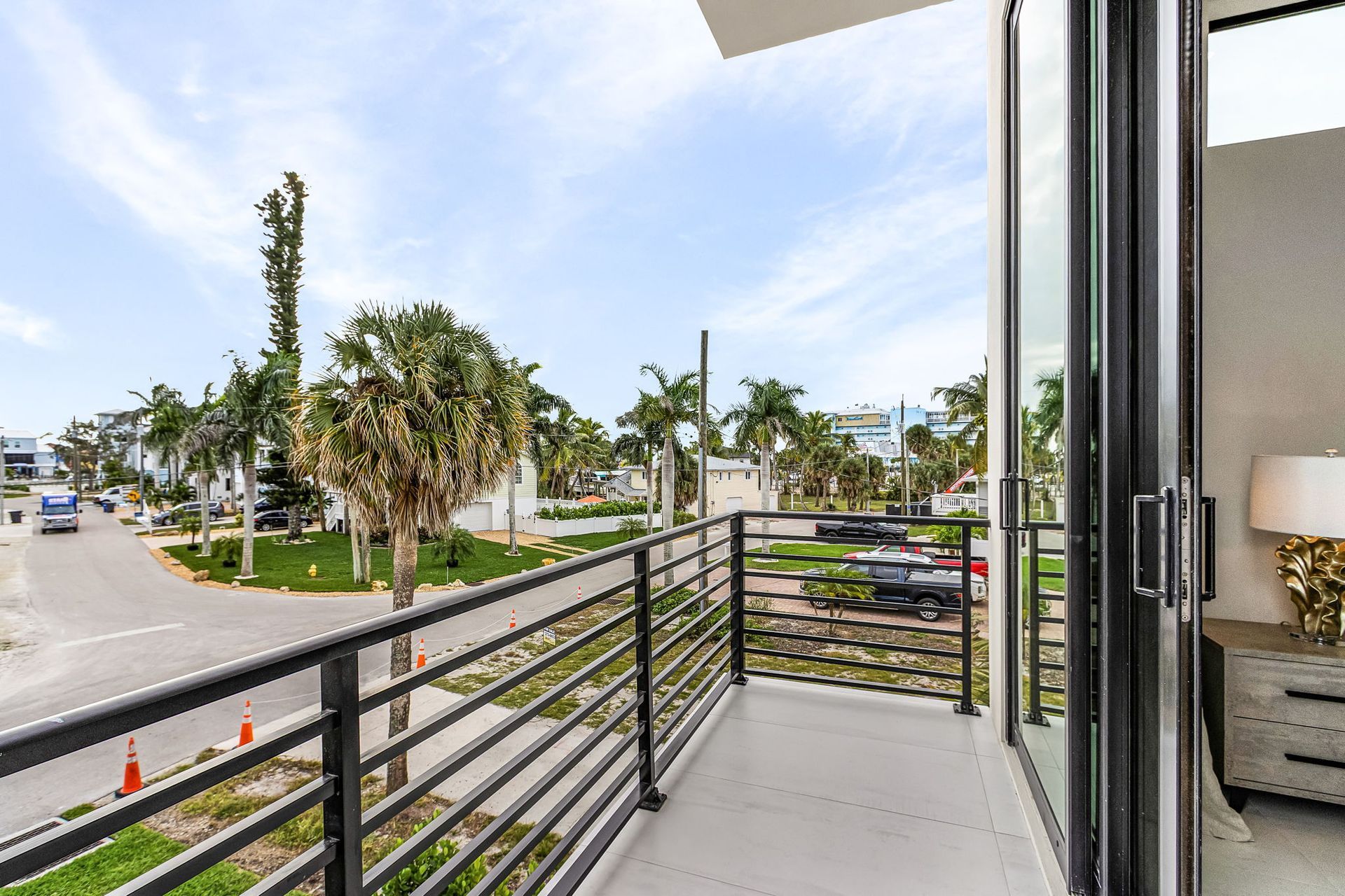 Balcony overlooking a street lined with palm trees.  A glass sliding door leads inside.