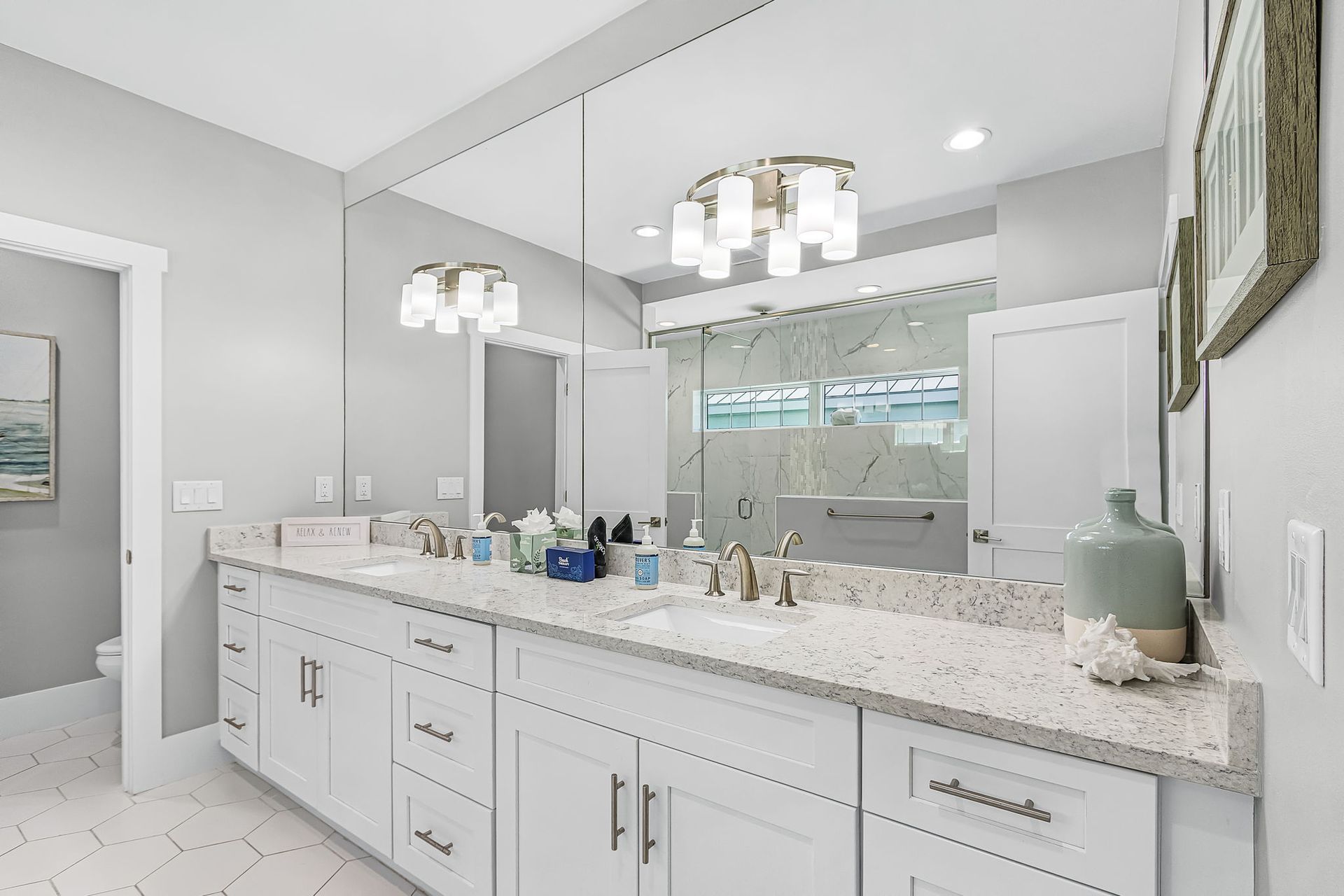 Bright modern bathroom vanity with double sinks, large mirror, and white cabinetry