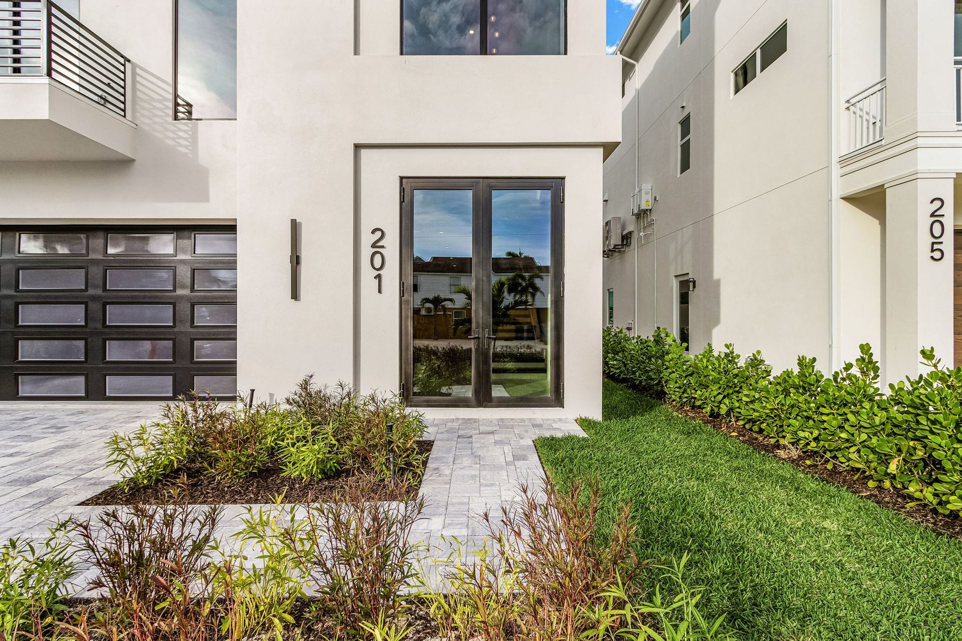 Modern house exterior with glass doors and garage, address 201.