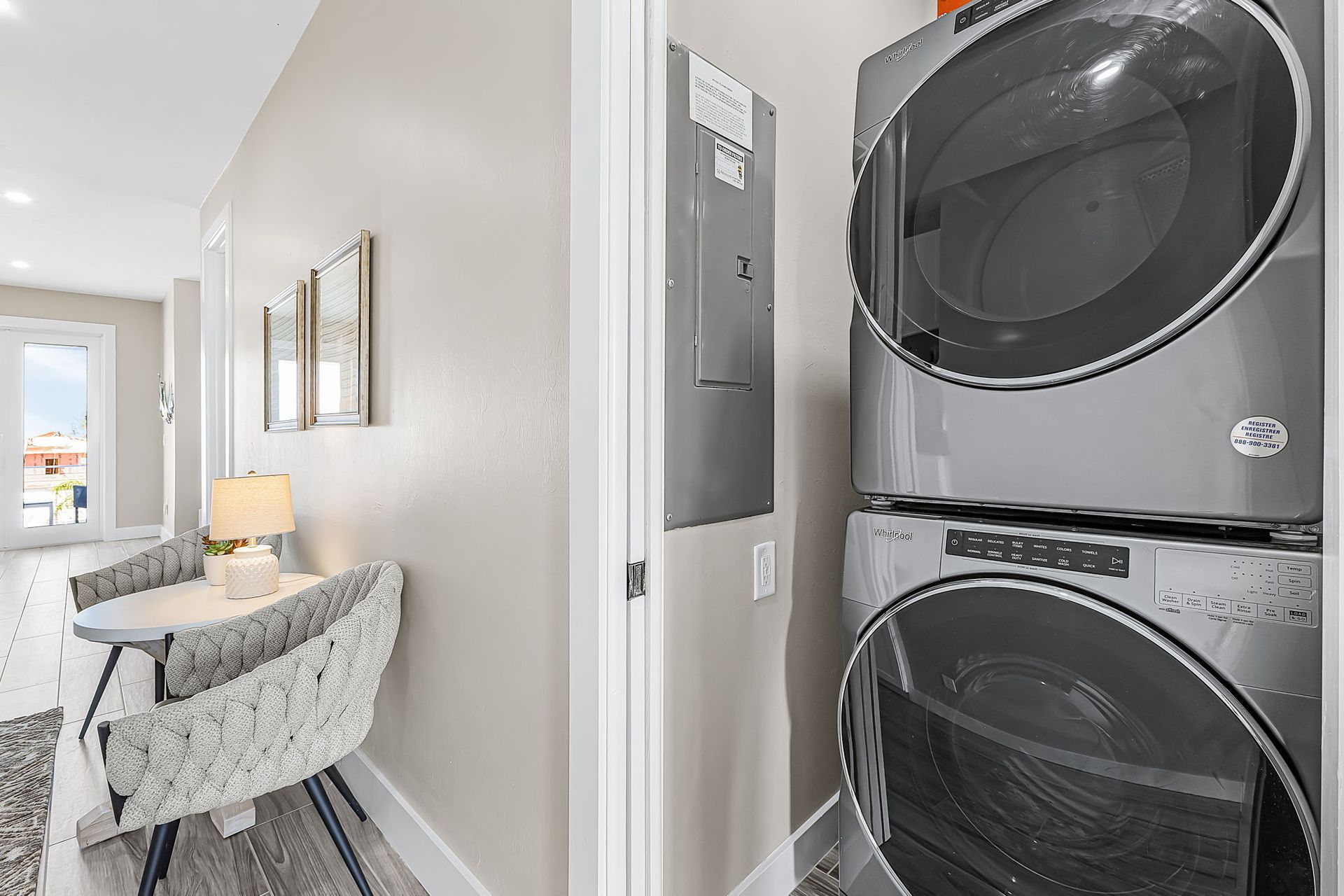 Hallway beside stacked washer and dryer, with a small desk and chair in a bright home interior