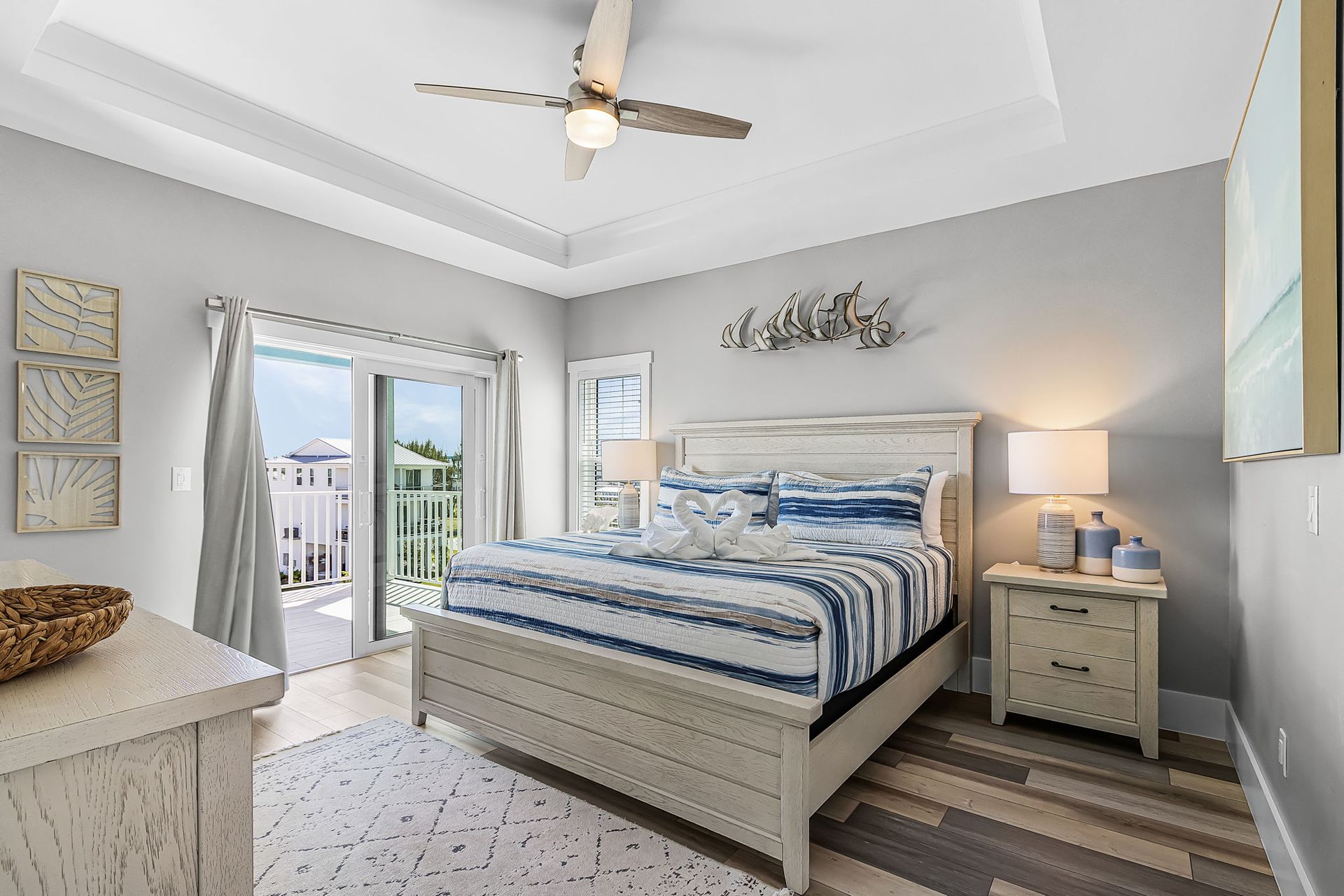 Bright bedroom with a striped bed, gray walls, bedside lamps, and balcony doors letting in daylight
