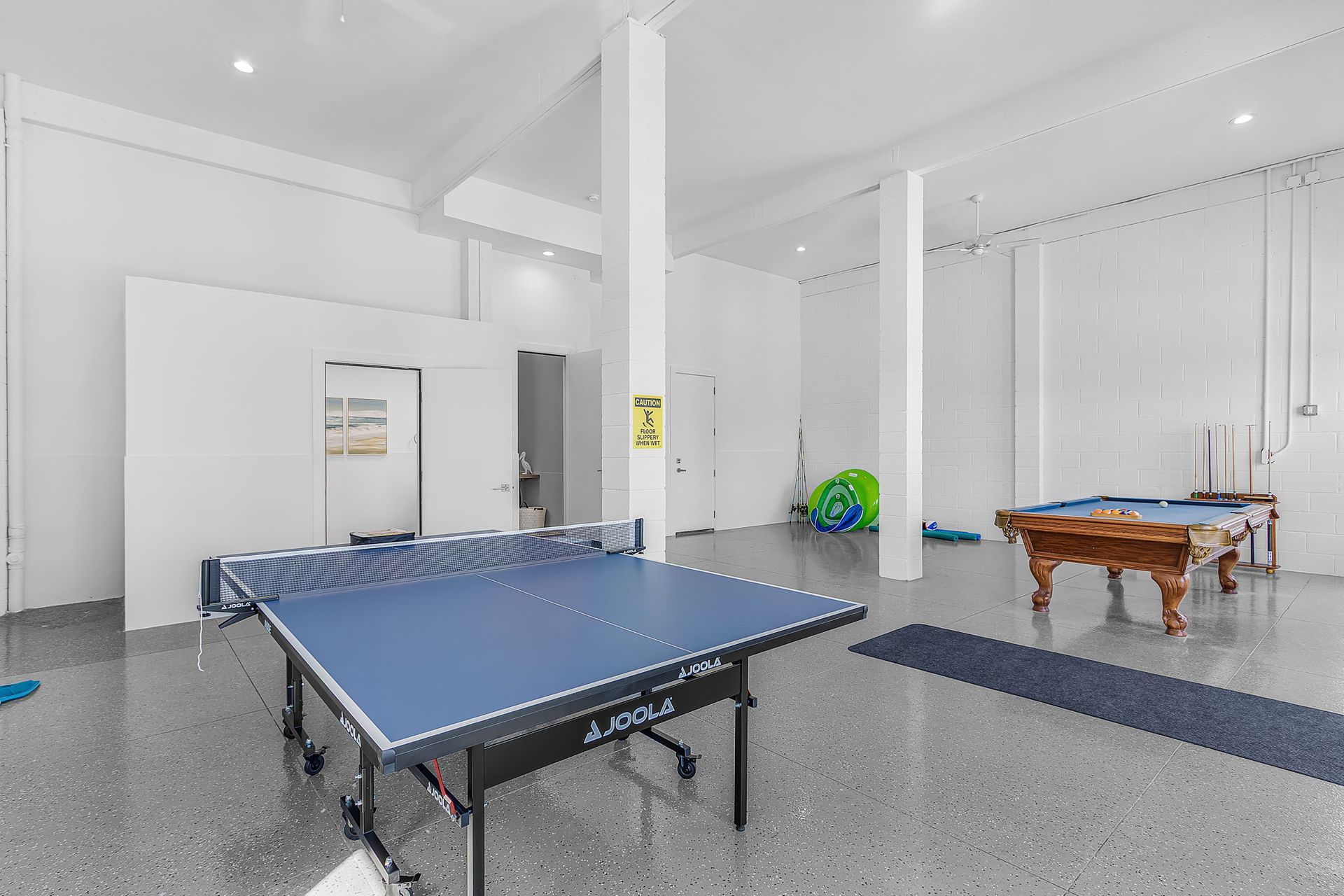 Bright recreation room with ping-pong and pool tables on a polished floor