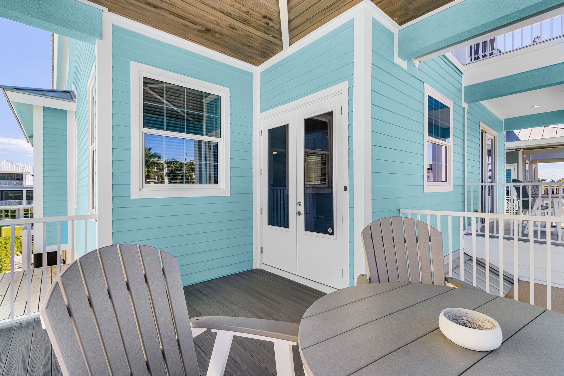 Turquoise beach house porch with white trim, chairs, and small table by the door