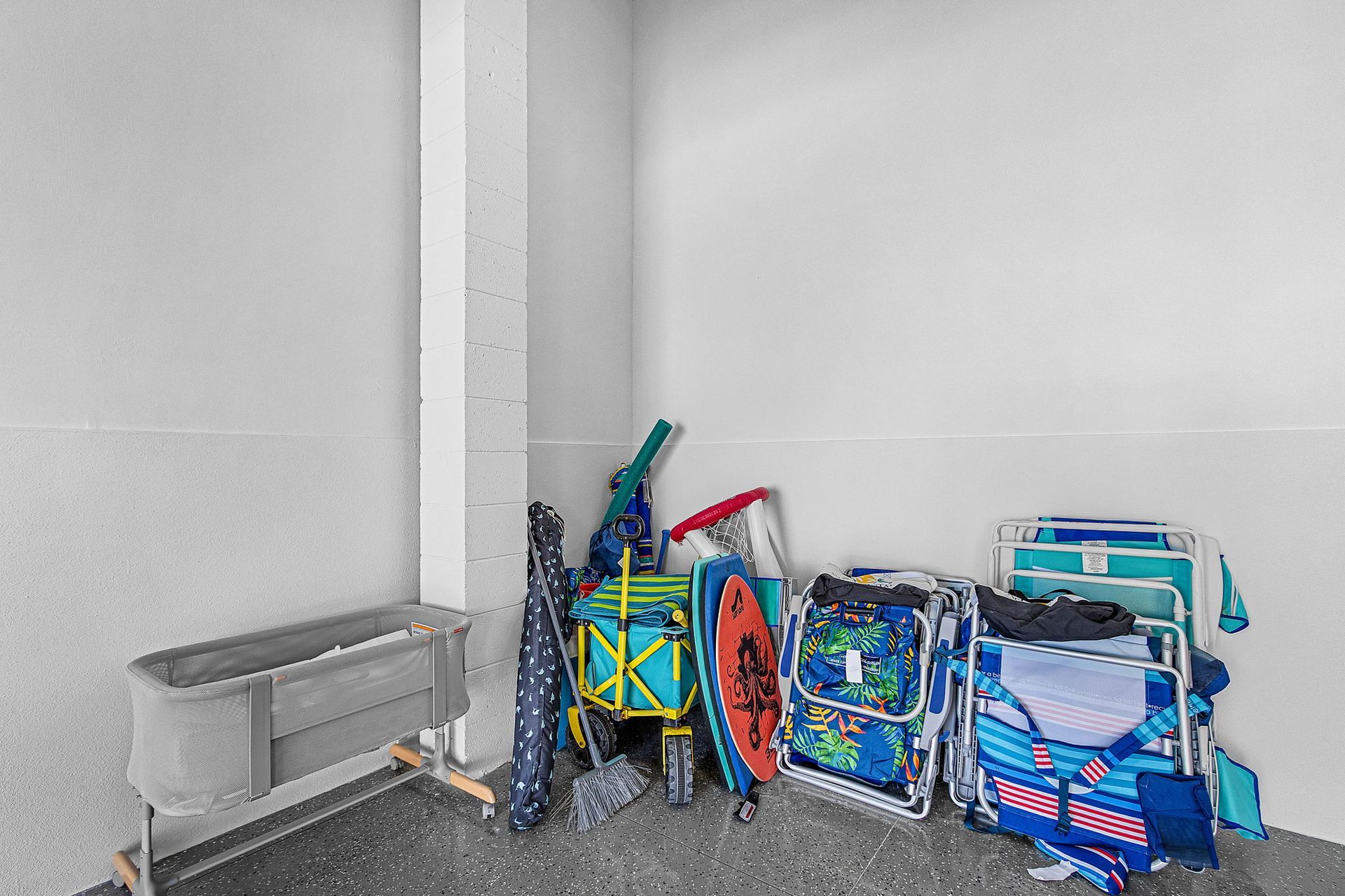 Folded beach chairs and gear stacked against a wall in a garage or storage area.
