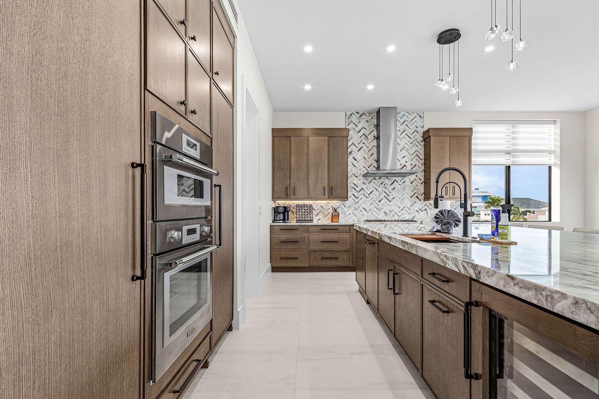 Modern kitchen with wood cabinets, granite island, built-in ovens, and large window view
