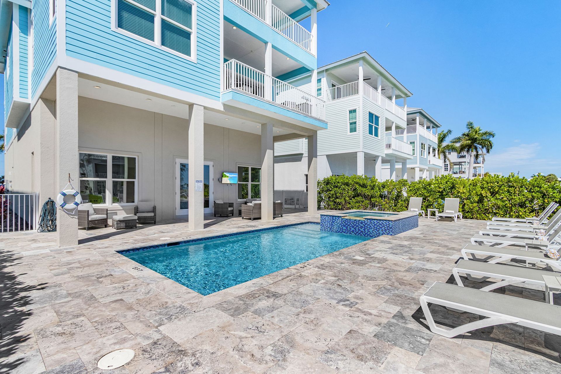 Luxurious condo courtyard with a small pool, lounge chairs, and turquoise-and-white balconies