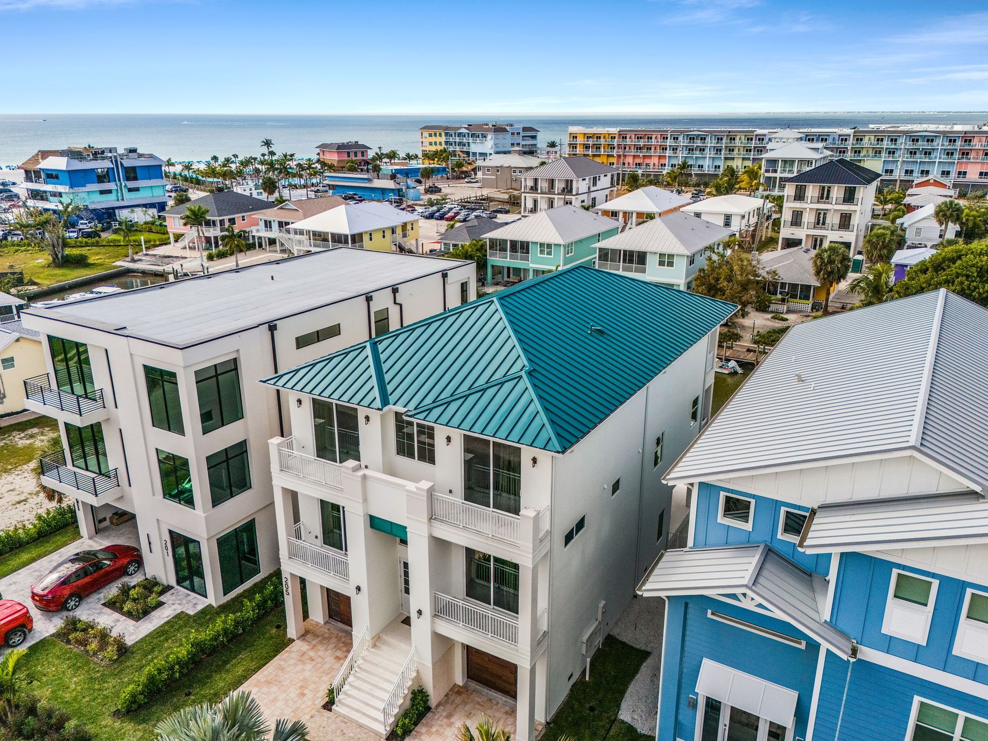 Aerial view of several colorful beach houses with ocean in background.